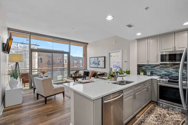 a living room with stainless steel appliances kitchen island granite countertop a sink and a stove