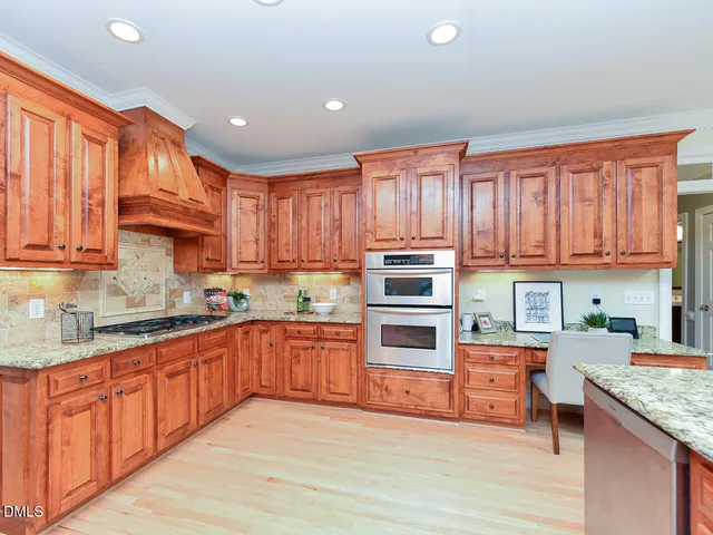 a kitchen with stainless steel appliances granite countertop a stove top oven a sink dishwasher and a refrigerator with wooden cabinets