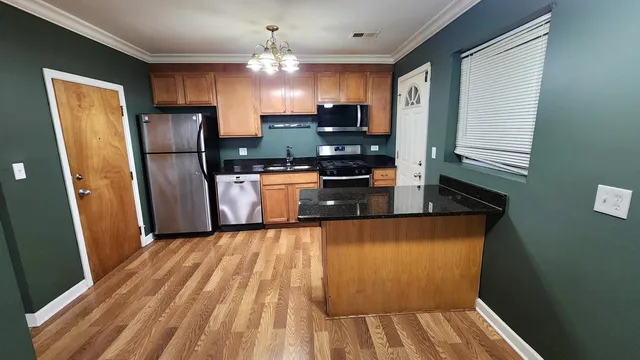 a kitchen with stainless steel appliances granite countertop a refrigerator a sink dishwasher a stove and white countertops with wooden floor