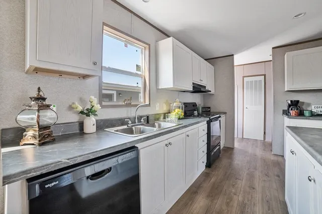 a kitchen with stainless steel appliances white cabinets a sink dishwasher a stove and white cabinets next to a window