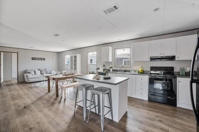 a kitchen with stainless steel appliances granite countertop a stove top oven a sink dishwasher a dining table and chairs with wooden floor