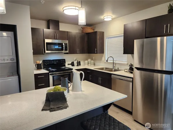a kitchen with a refrigerator a sink a stove a microwave a counter top space and cabinets