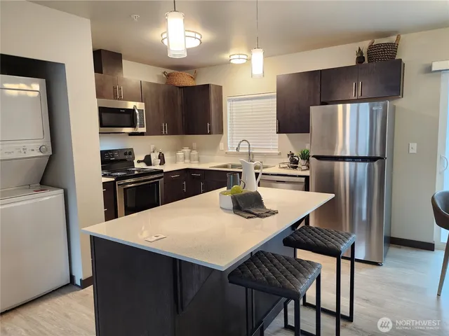 a kitchen with a sink a refrigerator and chairs