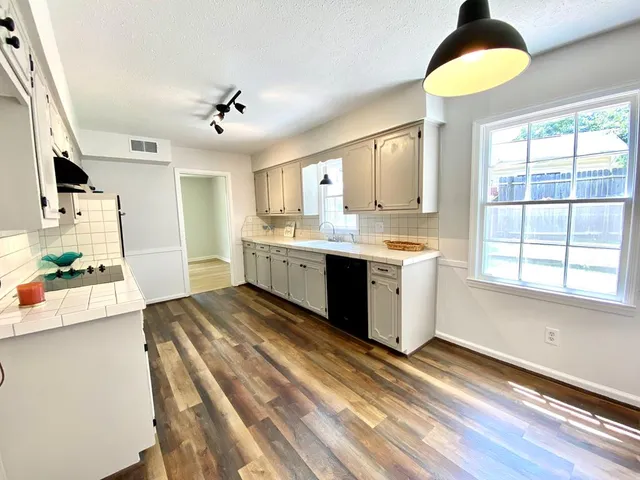 a large kitchen with stainless steel appliances granite countertop a stove a sink dishwasher and a dining table with wooden floor