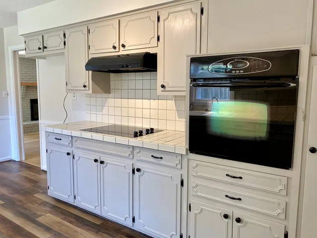 a kitchen with stainless steel appliances white cabinets and a stove top oven