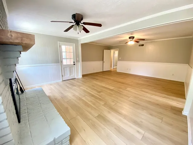 a view of a bedroom with wooden floor and a ceiling fan