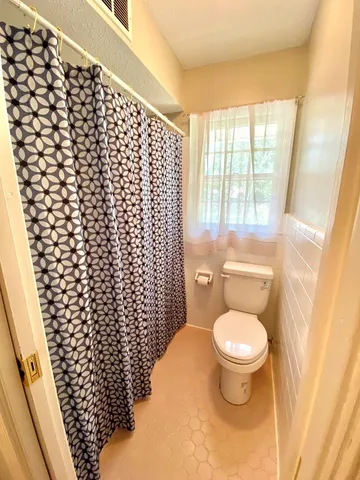 a bathroom with a toilet and a shower curtain