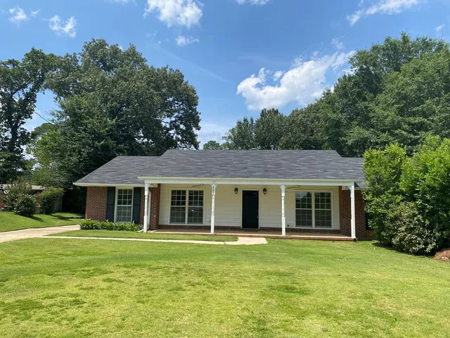 a view of a house with a backyard and a tree