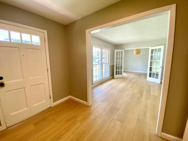 an empty room with wooden floor and windows