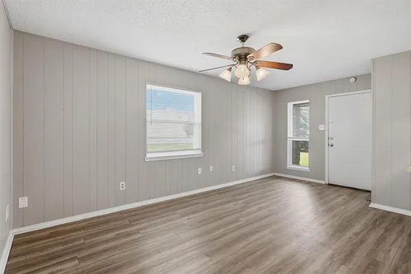 a view of an empty room with wooden floor and a window