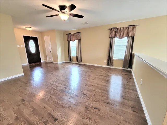 a view of an empty room with window and wooden floor