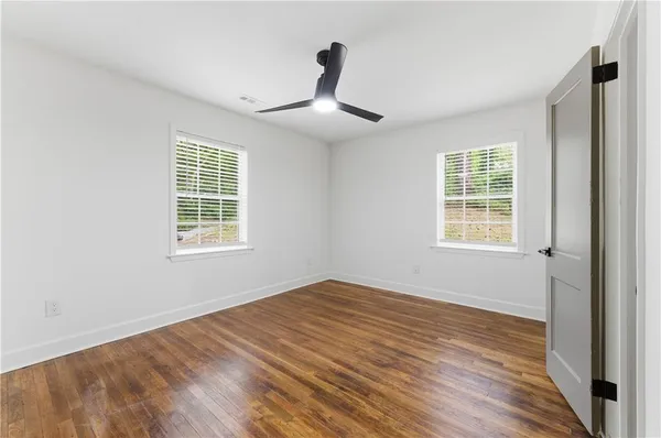 a view of empty room with wooden floor and fan