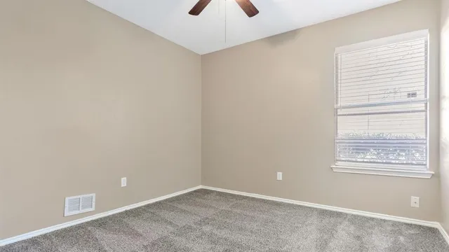 an empty room with a window and a ceiling fan