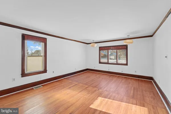 a view of an empty room with window and wooden floor