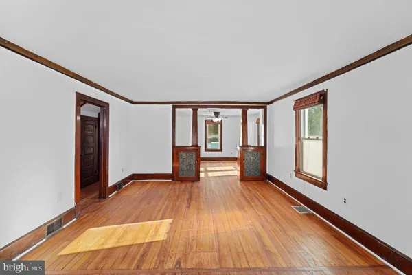 a view of empty room with wooden floor and fan