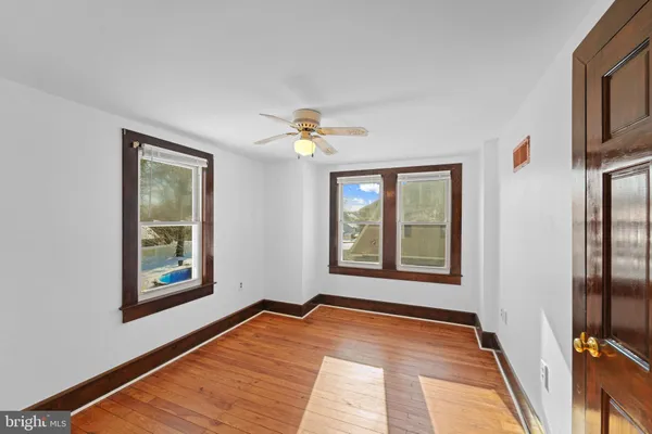 a view of an empty room with window and wooden floor