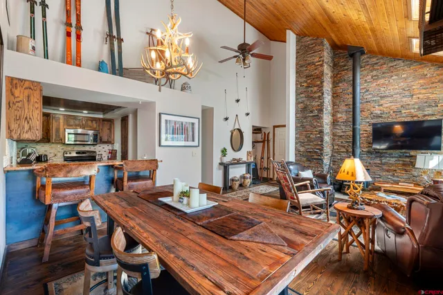 a view of a dining room with furniture one side kitchen view and wooden floor
