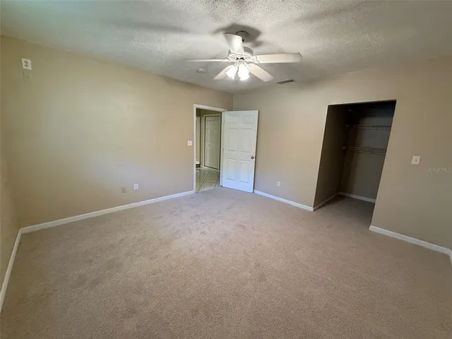 a view of an empty room with a chandelier fan