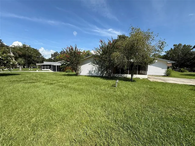 a view of a house with a big yard and palm trees
