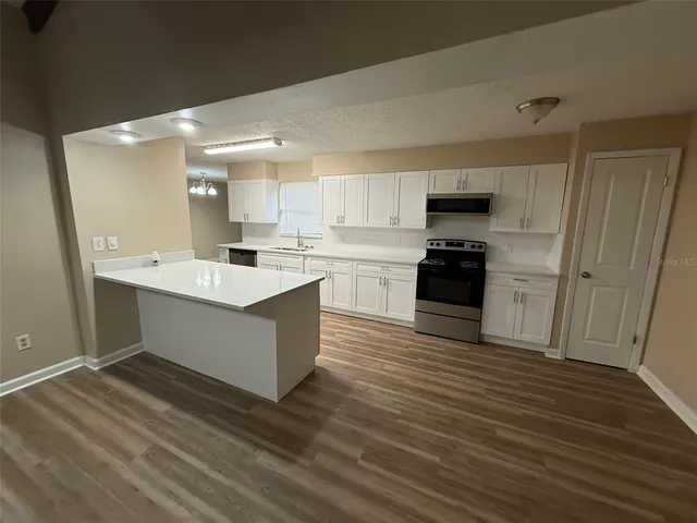 a large kitchen with cabinets wooden floor and stainless steel appliances