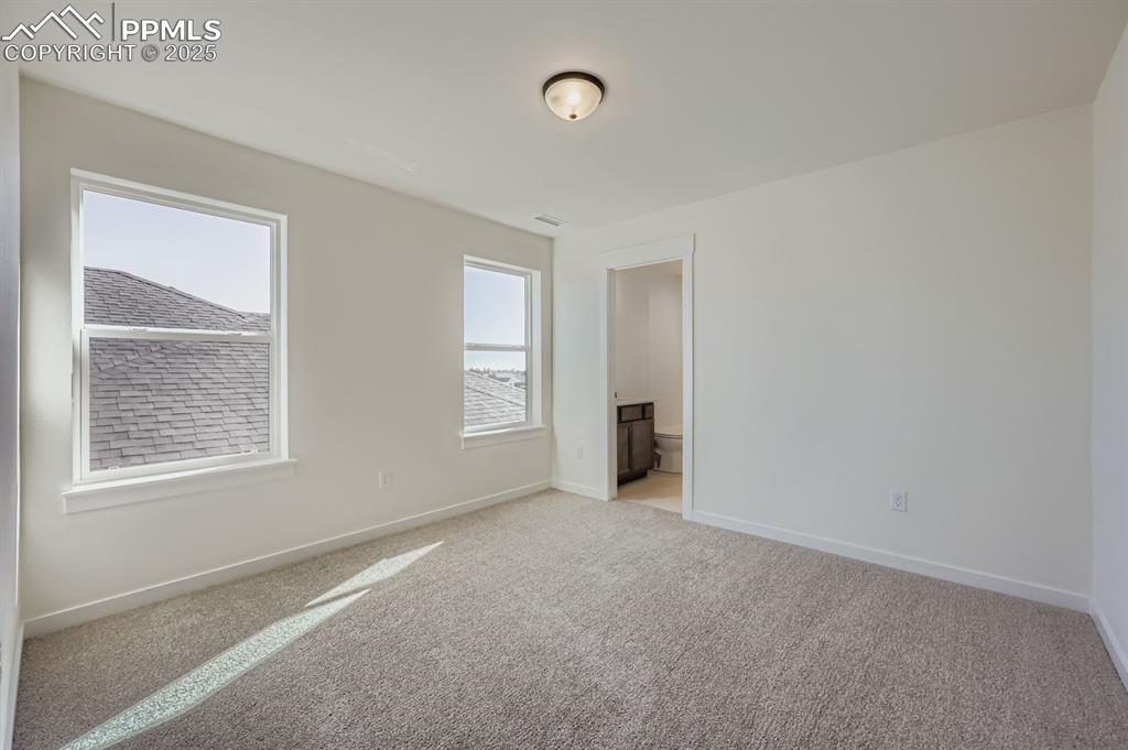 7989 Polson Drive Colorado Springs, CO 80908 - Photo 17 of 28 Unfurnished bedroom with light colored carpet and connected bathroom