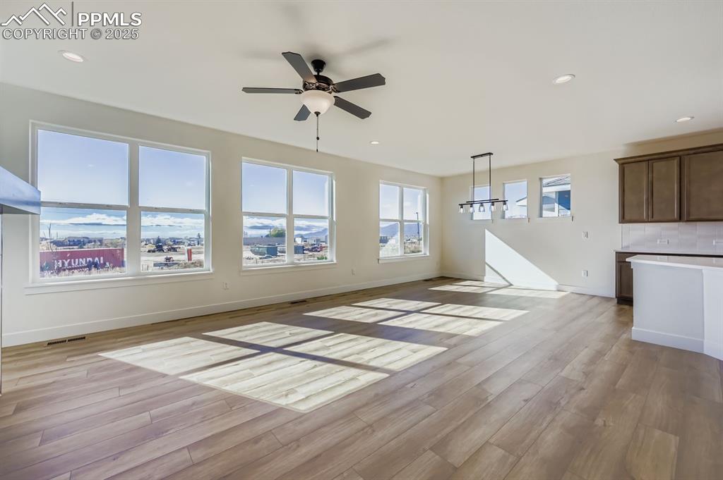 7989 Polson Drive Colorado Springs, CO 80908 - Photo 4 of 28 Unfurnished living room featuring recessed lighting, light wood finished floors, ceiling fan, and a chandelier