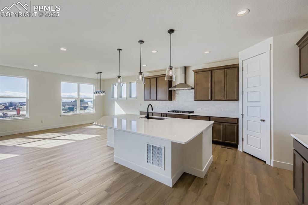 7989 Polson Drive Colorado Springs, CO 80908 - Photo 7 of 28 Kitchen featuring decorative light fixtures, recessed lighting, tasteful backsplash, light wood-style floors, and light stone countertops