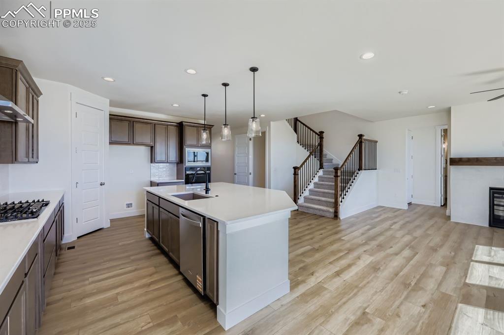 7989 Polson Drive Colorado Springs, CO 80908 - Photo 8 of 28 Kitchen with pendant lighting, a center island with sink, recessed lighting, light wood-type flooring, and appliances with stainless steel finishes