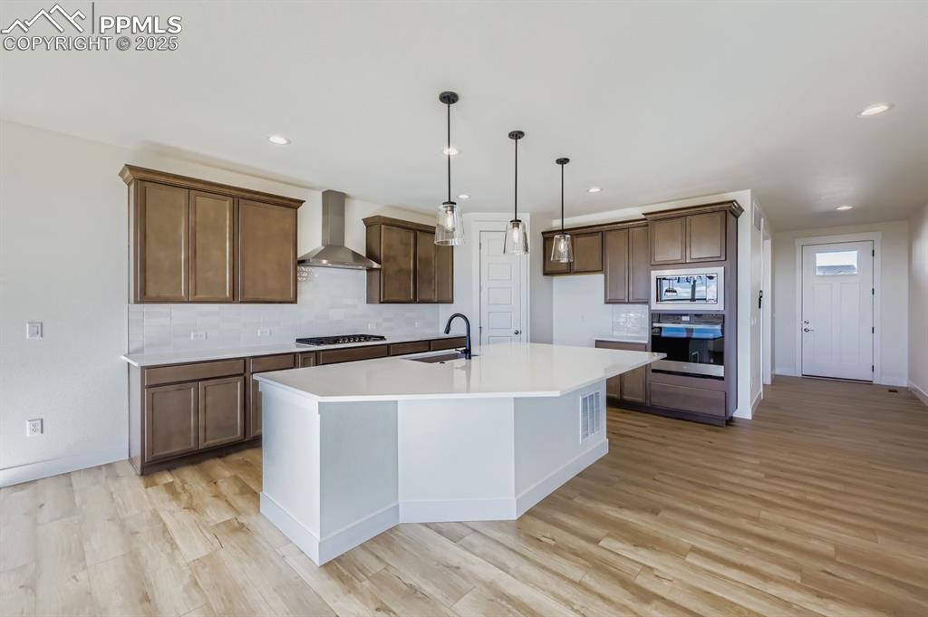 7989 Polson Drive Colorado Springs, CO 80908 - Photo 9 of 28 Kitchen with backsplash, stainless steel appliances, decorative light fixtures, light wood-style flooring, and recessed lighting