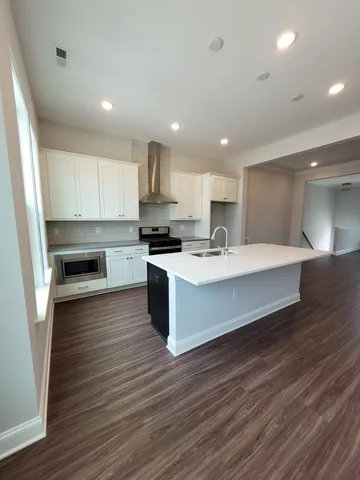 a large white kitchen with kitchen island a sink wooden floor and a stove