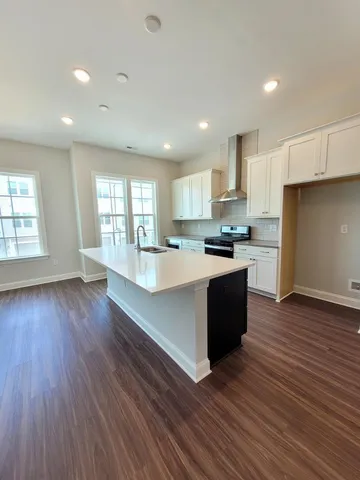 a large kitchen with stainless steel appliances granite countertop a large counter top a stove and a wooden floors