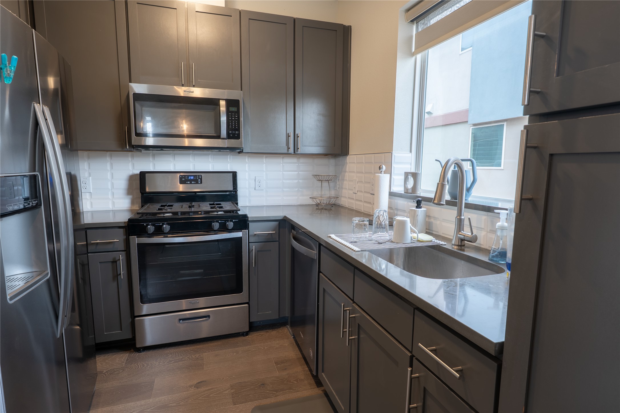 2827 Manor Road, Unit 4101 Austin, TX 78722 - Photo 13 of 38 Kitchen featuring stainless steel appliances, grey cabinetry, a stainless steel sink, and a window with natural light