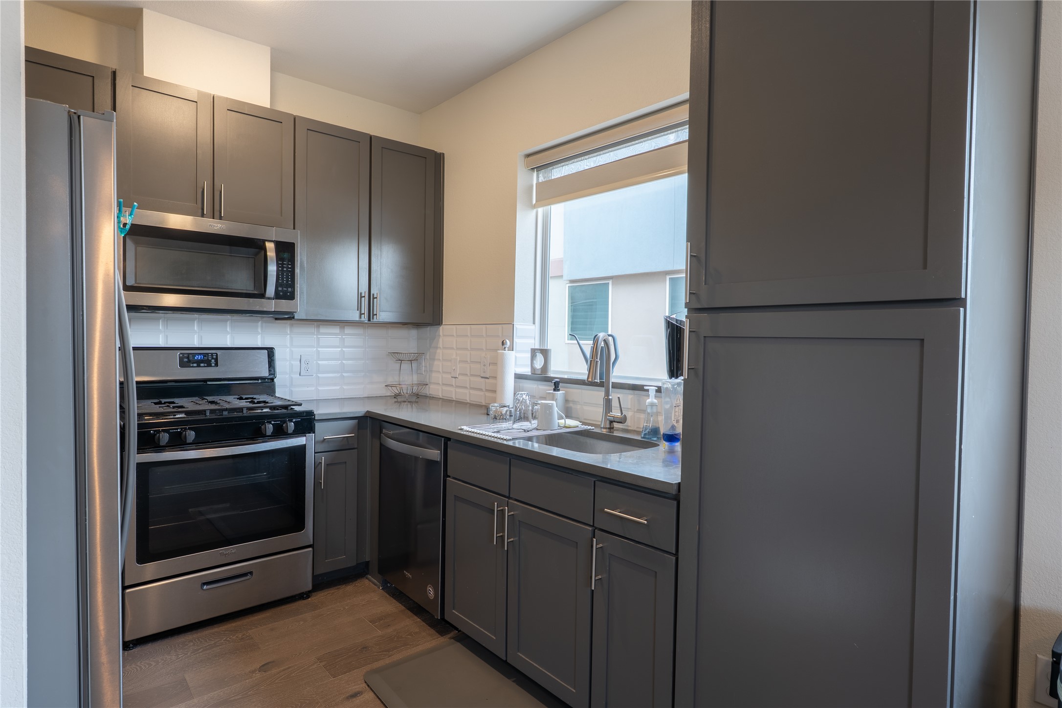 2827 Manor Road, Unit 4101 Austin, TX 78722 - Photo 16 of 38 The kitchen features stainless steel appliances, grey cabinetry, a stainless steel sink, and a window with a roller blind