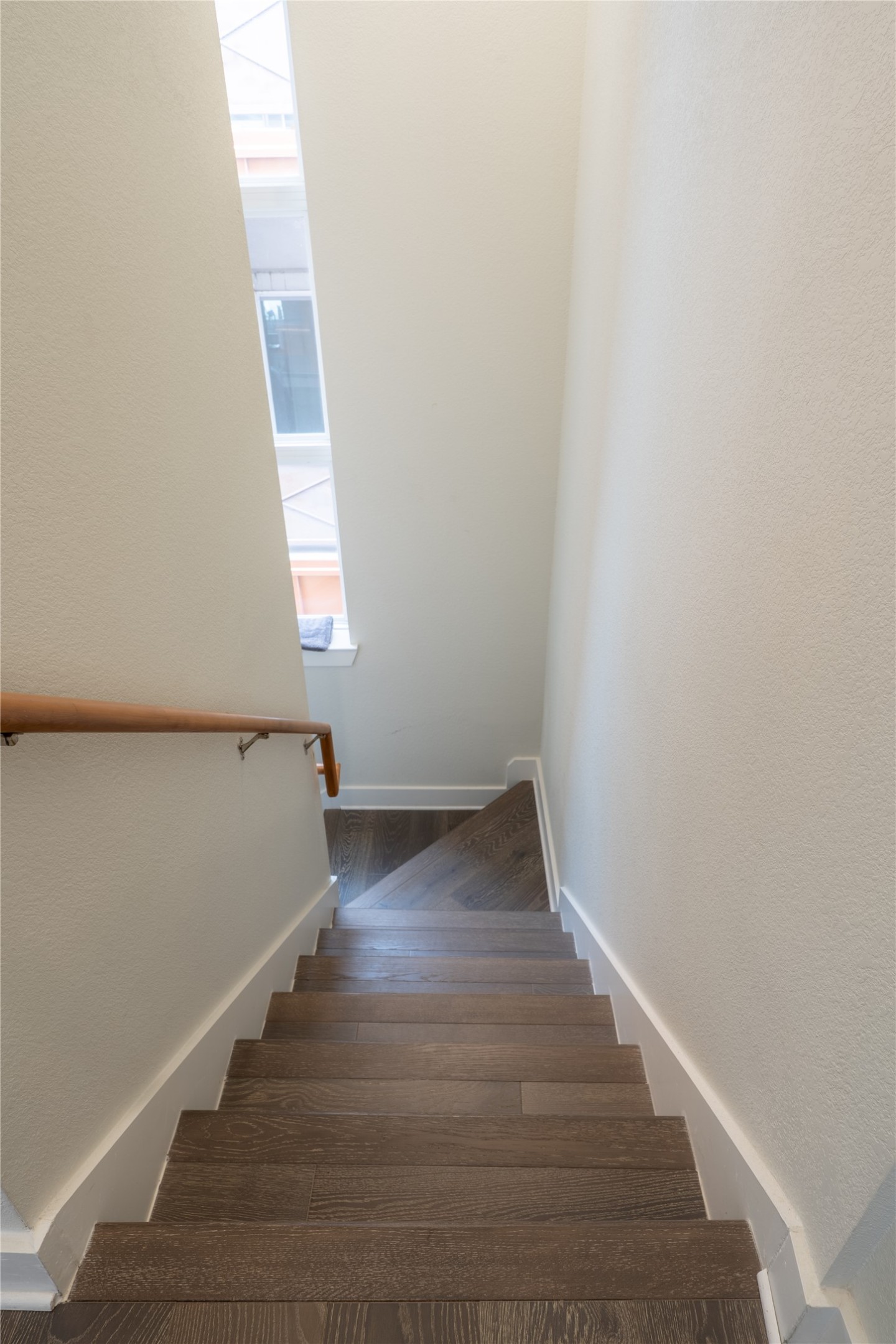 2827 Manor Road, Unit 4101 Austin, TX 78722 - Photo 19 of 38 Interior staircase featuring dark wood treads, white risers, and a natural wood handrail