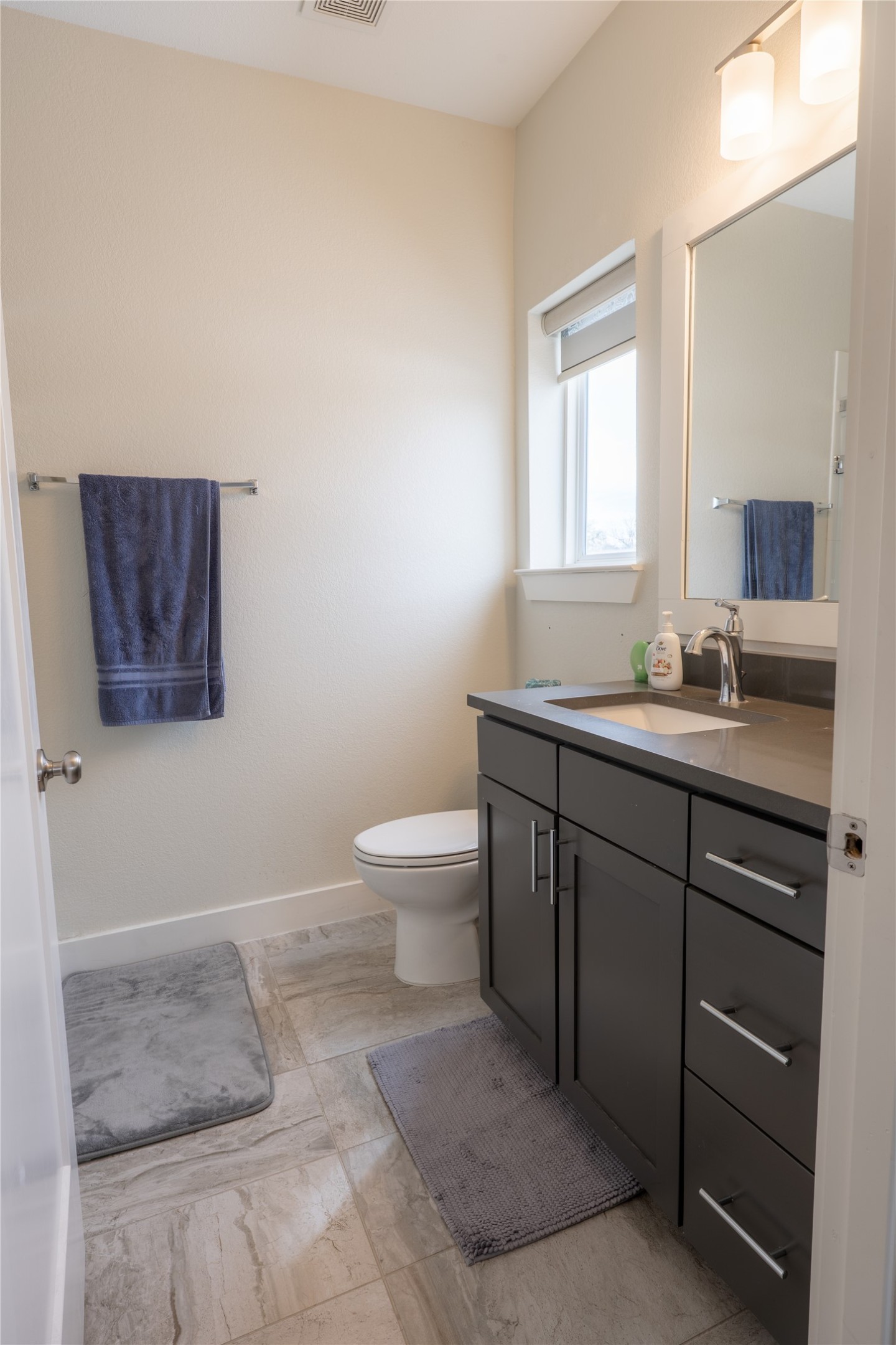 2827 Manor Road, Unit 4101 Austin, TX 78722 - Photo 20 of 38 The bathroom features a modern vanity with dark cabinetry, a countertop with an integrated sink, and a framed mirror above
