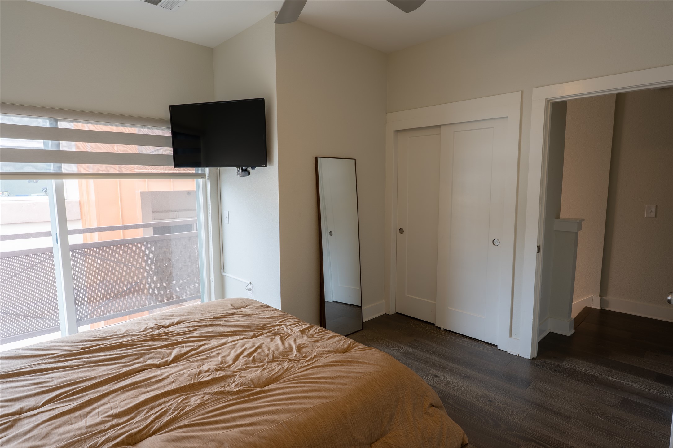 2827 Manor Road, Unit 4101 Austin, TX 78722 - Photo 24 of 38 This room features a sliding glass door with blinds, dark wood flooring, and a ceiling fan