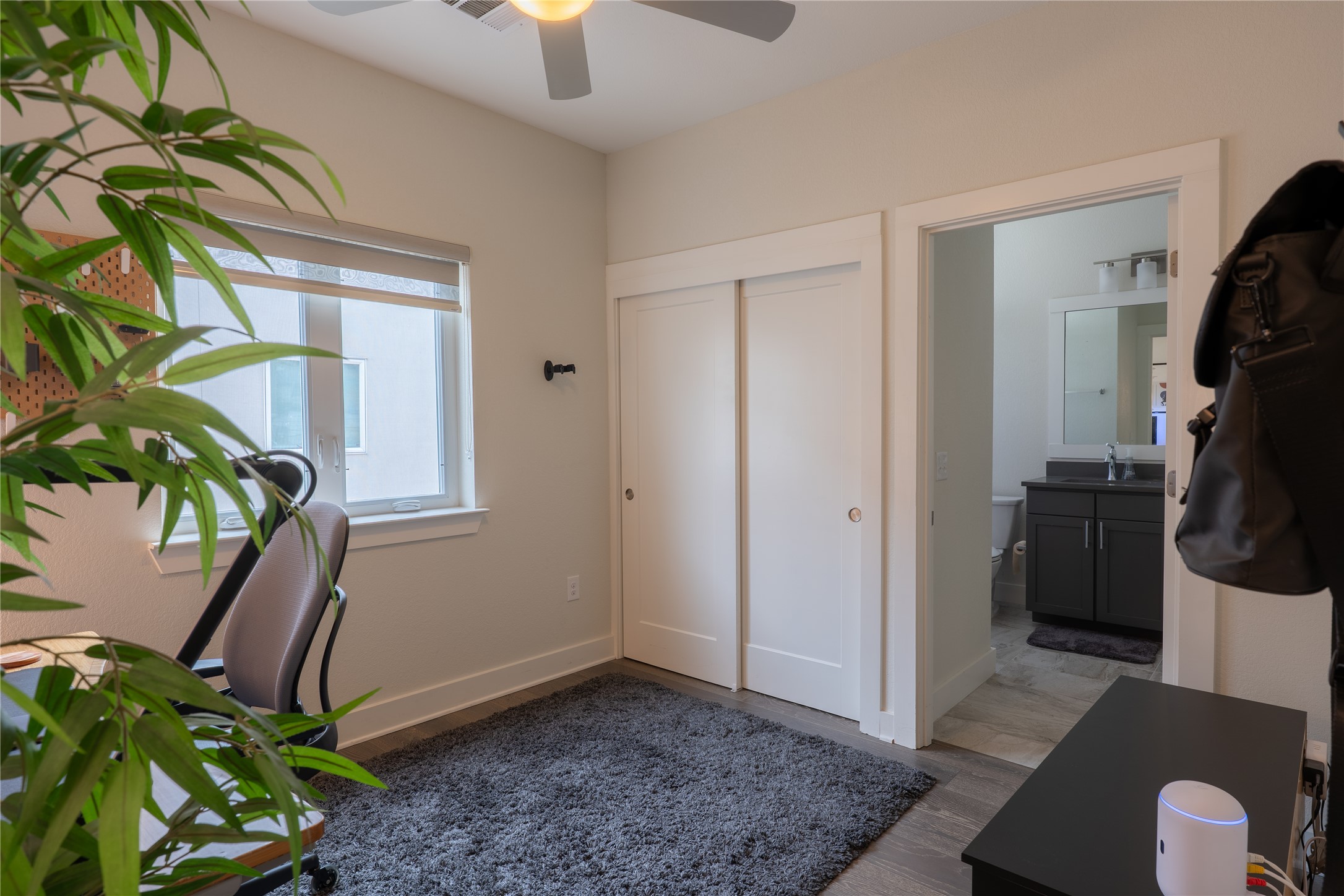 2827 Manor Road, Unit 4101 Austin, TX 78722 - Photo 29 of 38 This room features a window with a roller shade, a ceiling fan with integrated lighting, and a closet with sliding doors