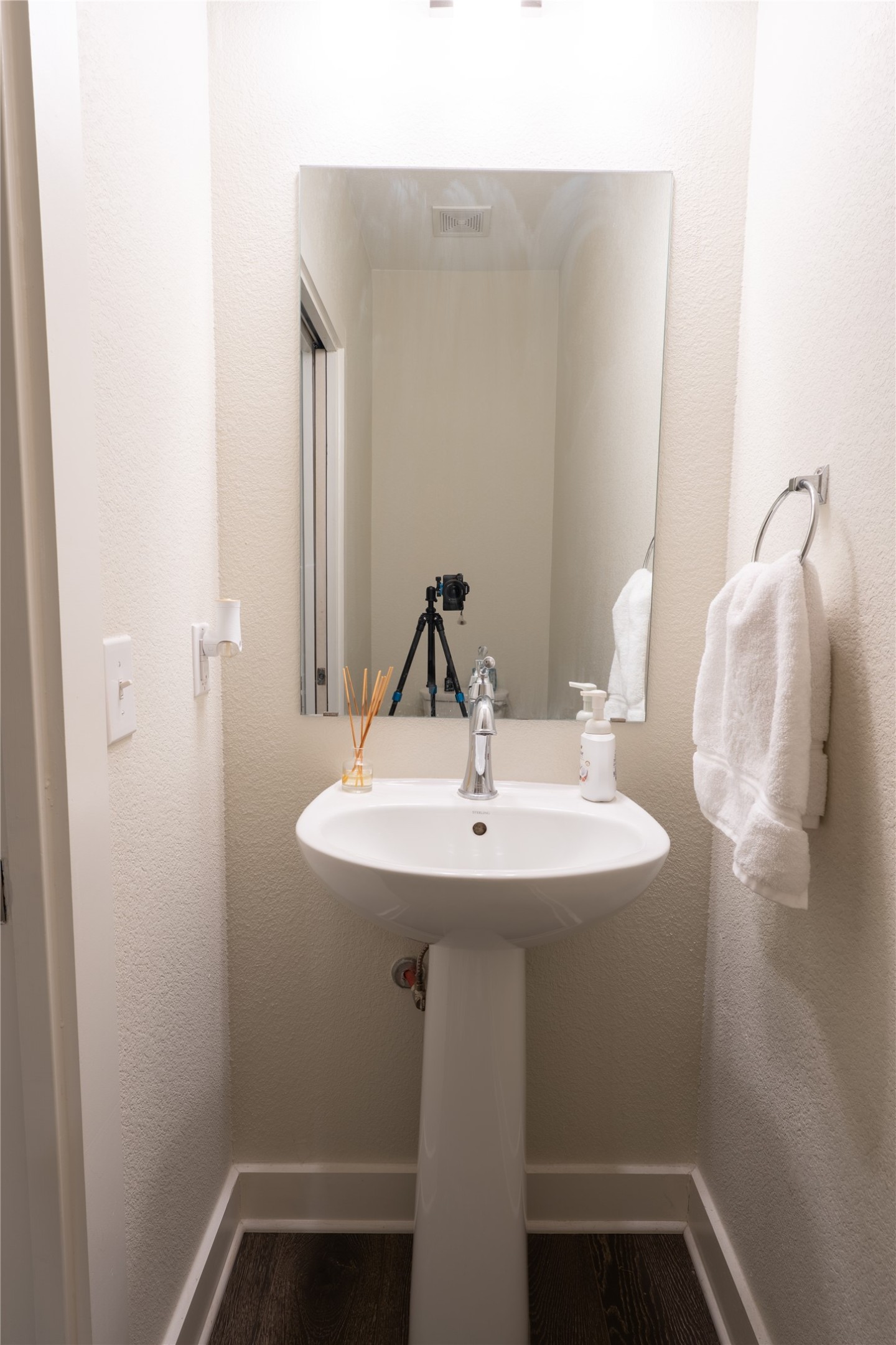 2827 Manor Road, Unit 4101 Austin, TX 78722 - Photo 3 of 38 This powder room features a white pedestal sink with a chrome faucet, a rectangular mirror, and dark wood-style flooring