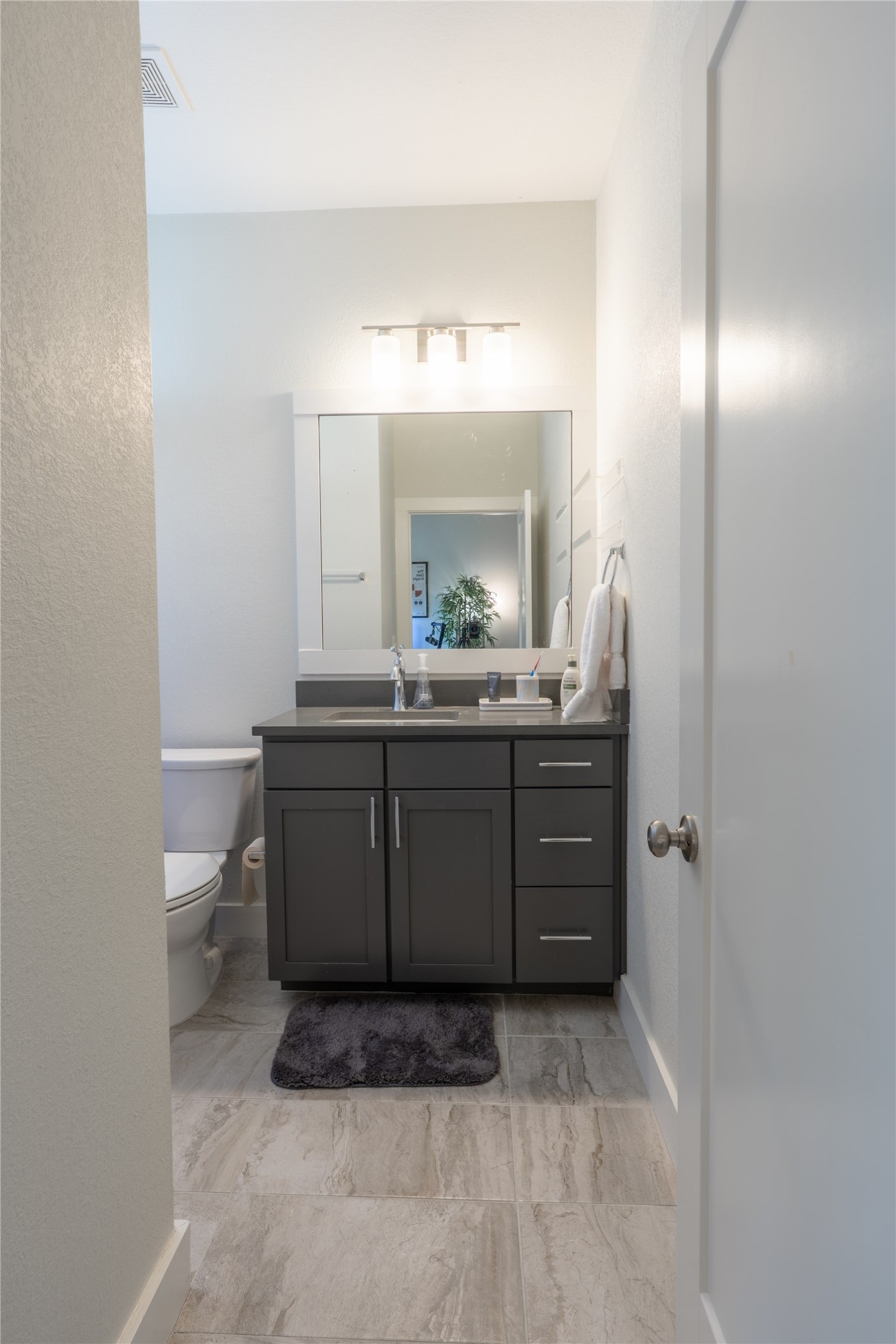 2827 Manor Road, Unit 4101 Austin, TX 78722 - Photo 31 of 38 The bathroom features a toilet, a vanity with a dark countertop and gray cabinetry, and tile flooring