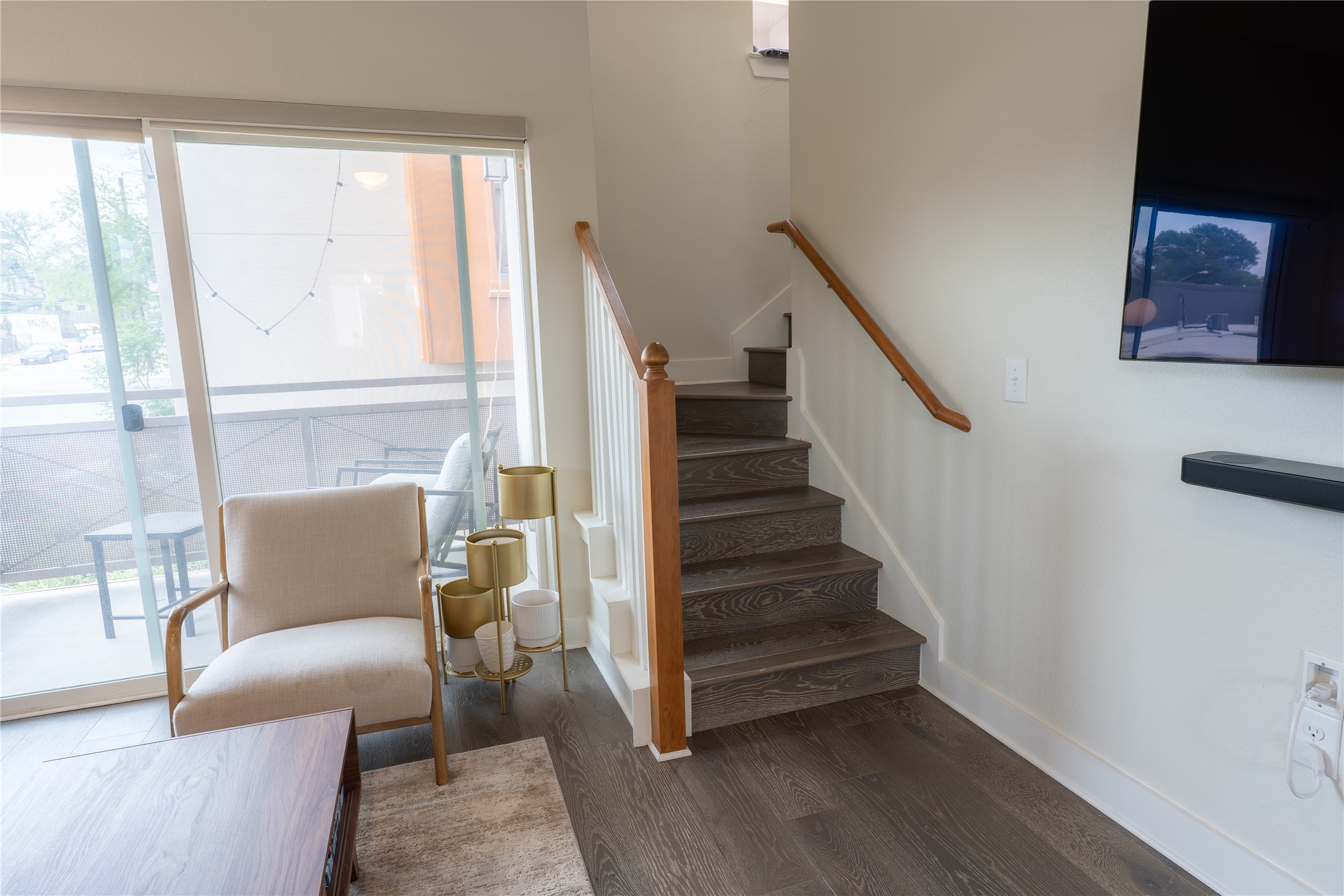 2827 Manor Road, Unit 4101 Austin, TX 78722 - Photo 4 of 38 The living area features wood flooring, a staircase with a wooden handrail, and direct access to a balcony through sliding glass doors