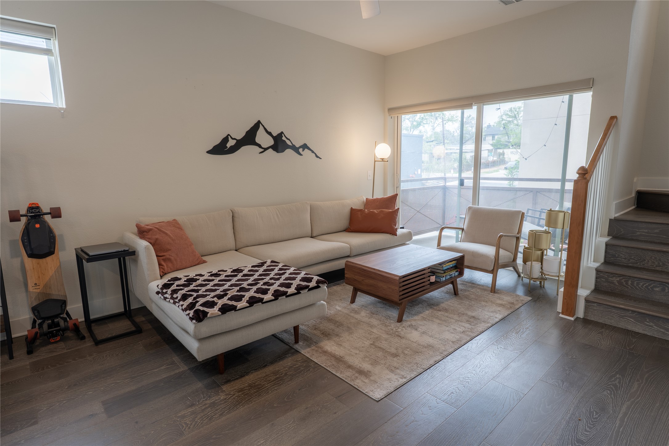 2827 Manor Road, Unit 4101 Austin, TX 78722 - Photo 5 of 38 The property features dark wood flooring, a spacious living area with large glass sliding doors, and a staircase with a wooden banister