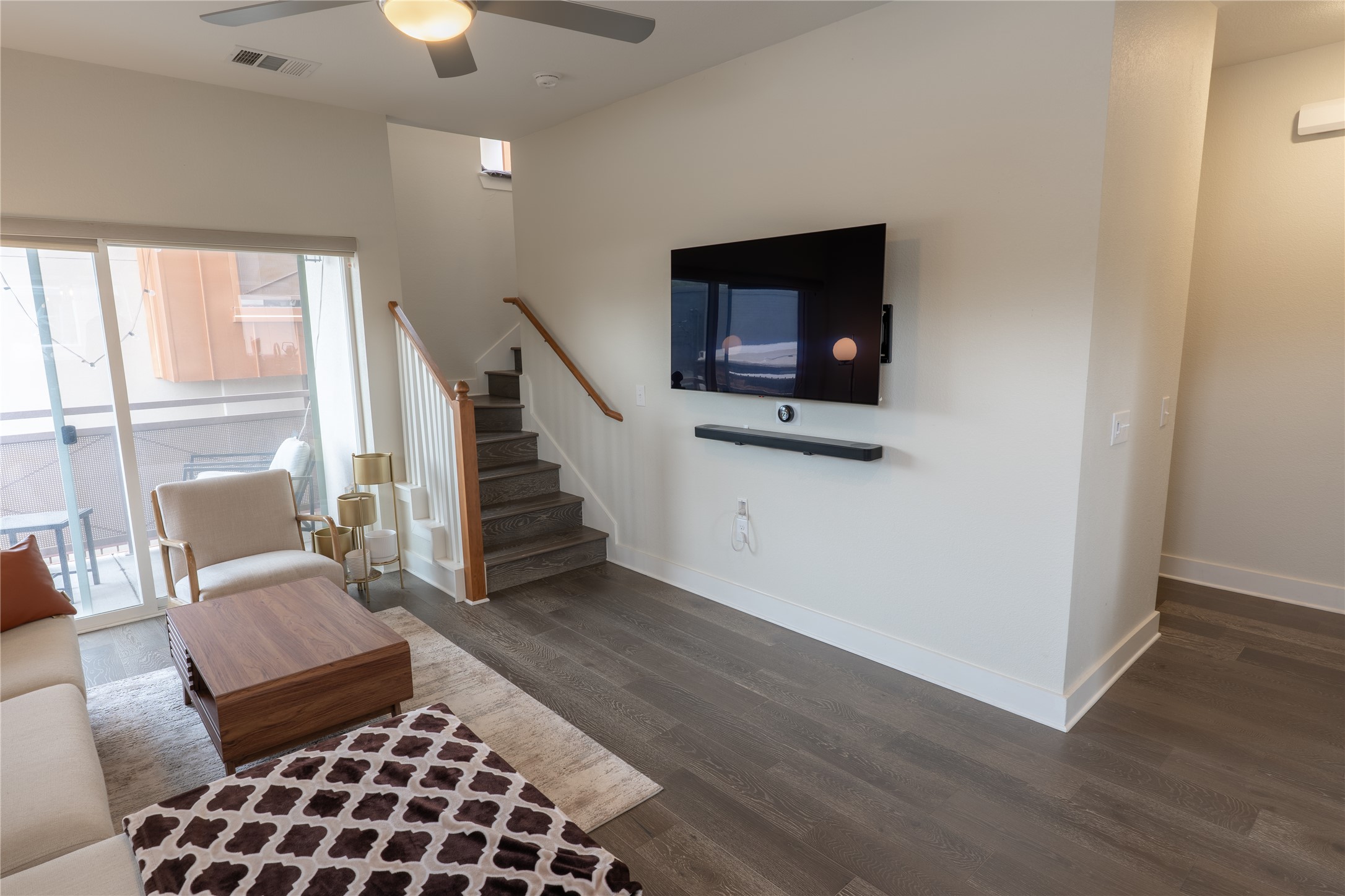 2827 Manor Road, Unit 4101 Austin, TX 78722 - Photo 7 of 38 Living area featuring hardwood floors, a ceiling fan with integrated lighting, and a staircase with a wooden handrail