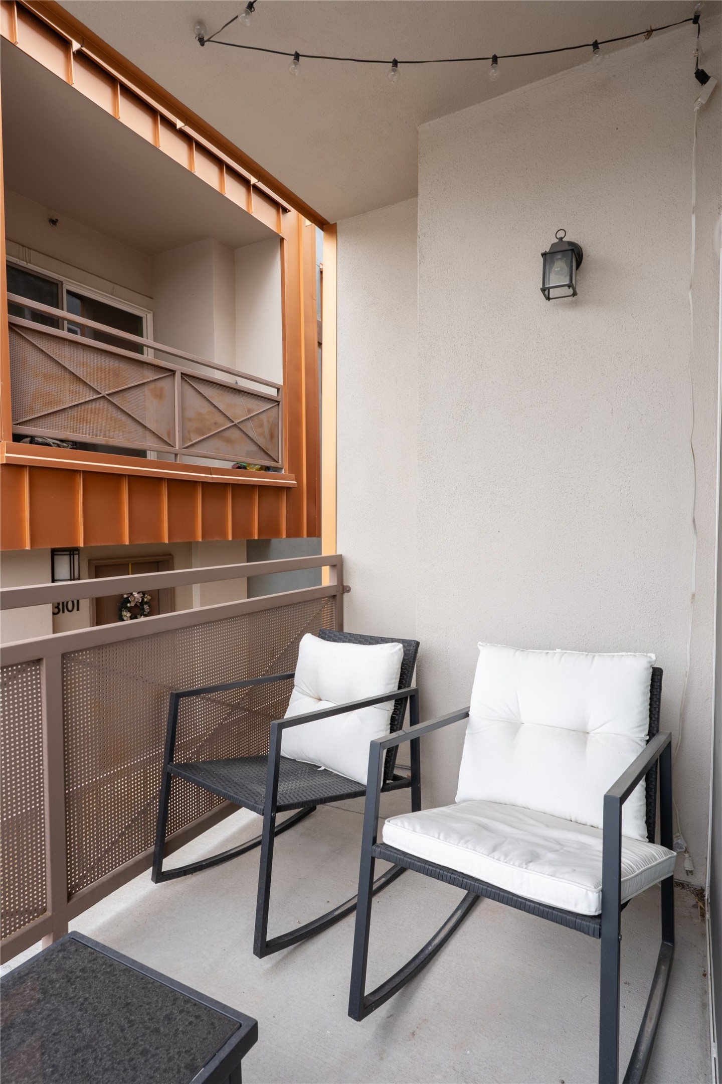 2827 Manor Road, Unit 4101 Austin, TX 78722 - Photo 8 of 38 Outdoor patio area featuring string lighting, a wall-mounted lantern, and a metal railing