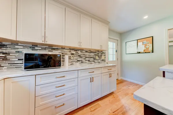 a kitchen with stainless steel appliances kitchen island granite countertop a refrigerator a stove a sink a dining table and chairs with wooden floor