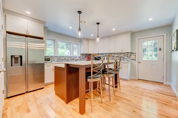 a kitchen with stainless steel appliances kitchen island granite countertop wooden floors and white cabinets
