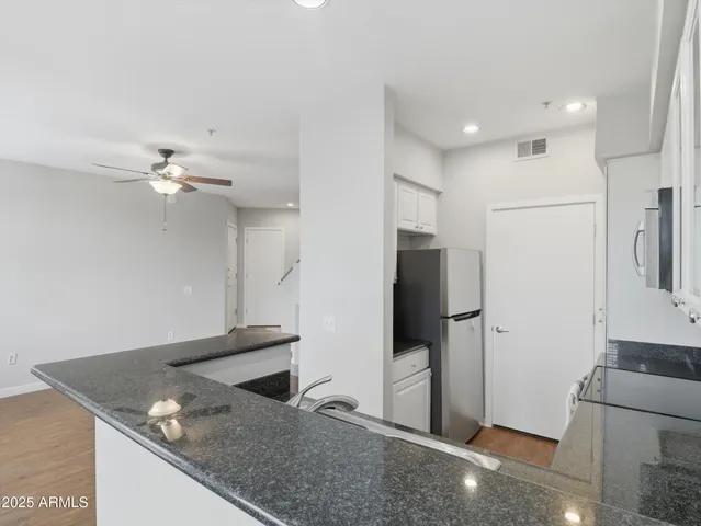 a kitchen with stainless steel appliances granite countertop a refrigerator a sink and white cabinets