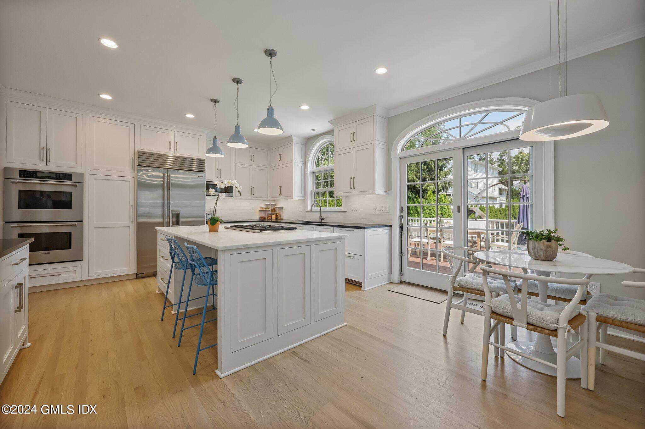 4 Grimes Road Old Greenwich, CT 06870 - Photo 3 of 22 a kitchen with stainless steel appliances kitchen island granite countertop a stove a refrigerator a sink a dining table and chairs with wooden floor