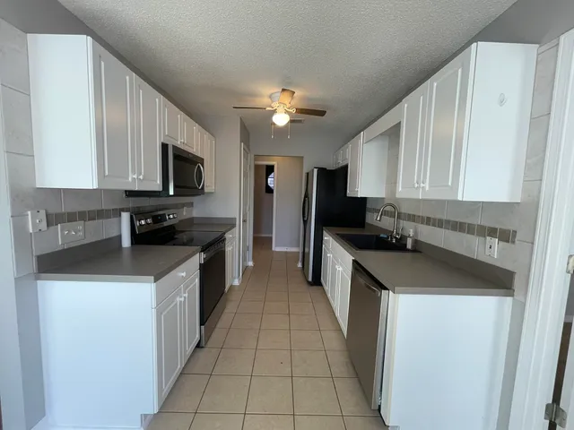 a kitchen with stainless steel appliances granite countertop a sink a stove top oven a refrigerator cabinets and a window