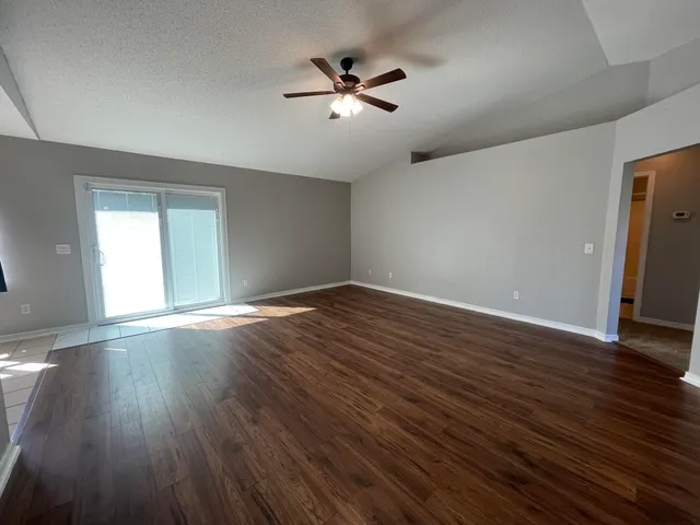an empty room with wooden floor and ceiling fan