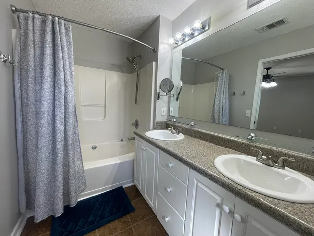 a bathroom with a granite countertop sink a mirror a shower and a bathtub